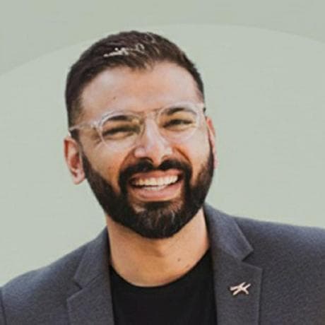 Manav Thaker, smiling, in glasses and a grey blazer.